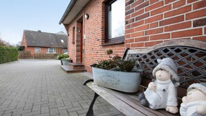 Een bakstenen gebouw met een bankje, een bloempot en twee decoratieve beeldjes.