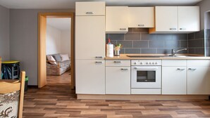 Een moderne keuken met witte kasten, een inbouwoven en een houten aanrecht.