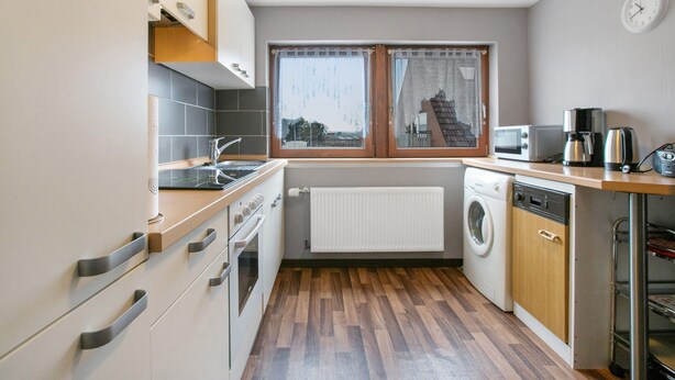 Een functionele keuken met een kookplaat, oven, magnetron en wasmachine.