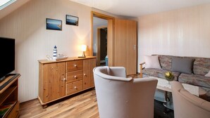 Een kamer met een houten kast, een televisie, een bank en een tafel met een vaas.