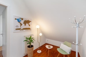 Une pièce comprenant une carte du monde, un lampadaire, un radiateur, une plante en pot, une chaise et un porte-manteau.