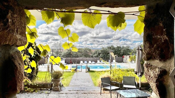 A covered outdoor area with a pool, chairs, and a table.