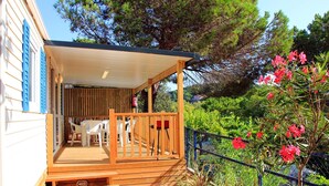 A wooden deck with a covered seating area, a fire extinguisher, and a fence. - Bungalow in Calella with Sea & Mountain Views (Calella)