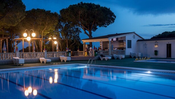 A swimming pool with lounge chairs and a covered area, surrounded by trees and a building. - Bungalow in Calella with Sea & Mountain Views (Calella)