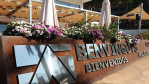 A sign with the text "BENVINGUOS BIENVENIDOS" and a logo, surrounded by flowers and umbrellas. - Bungalow in Calella with Sea & Mountain Views (Calella)