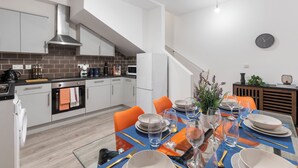 A modern kitchen with white cabinets, a stainless steel range hood, and a built-in oven. - Amazingly Beautiful 3 BR Flat For Large Groups (London)