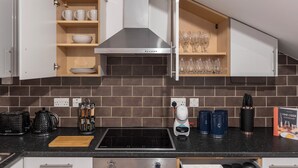 A modern kitchen with a built-in stove, a coffee maker, and a coffee grinder. There are cabinets with glassware and a cookbook on the counter. - Amazingly Beautiful 3 BR Flat For Large Groups (London)
