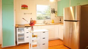Una cocina con armarios color turquesa, un refrigerador de acero inoxidable, un ventanal con vistas y un ventilador de techo.
