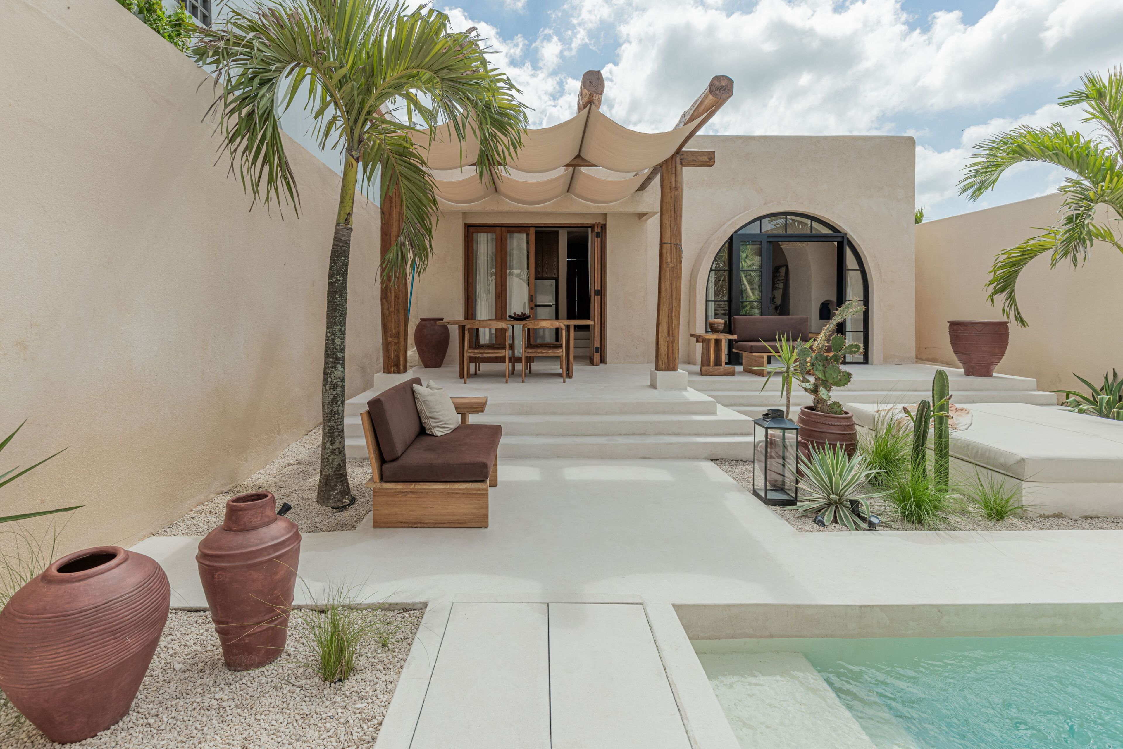Un área lounge moderna al aire libre con piscina, asientos y plantas en macetas.