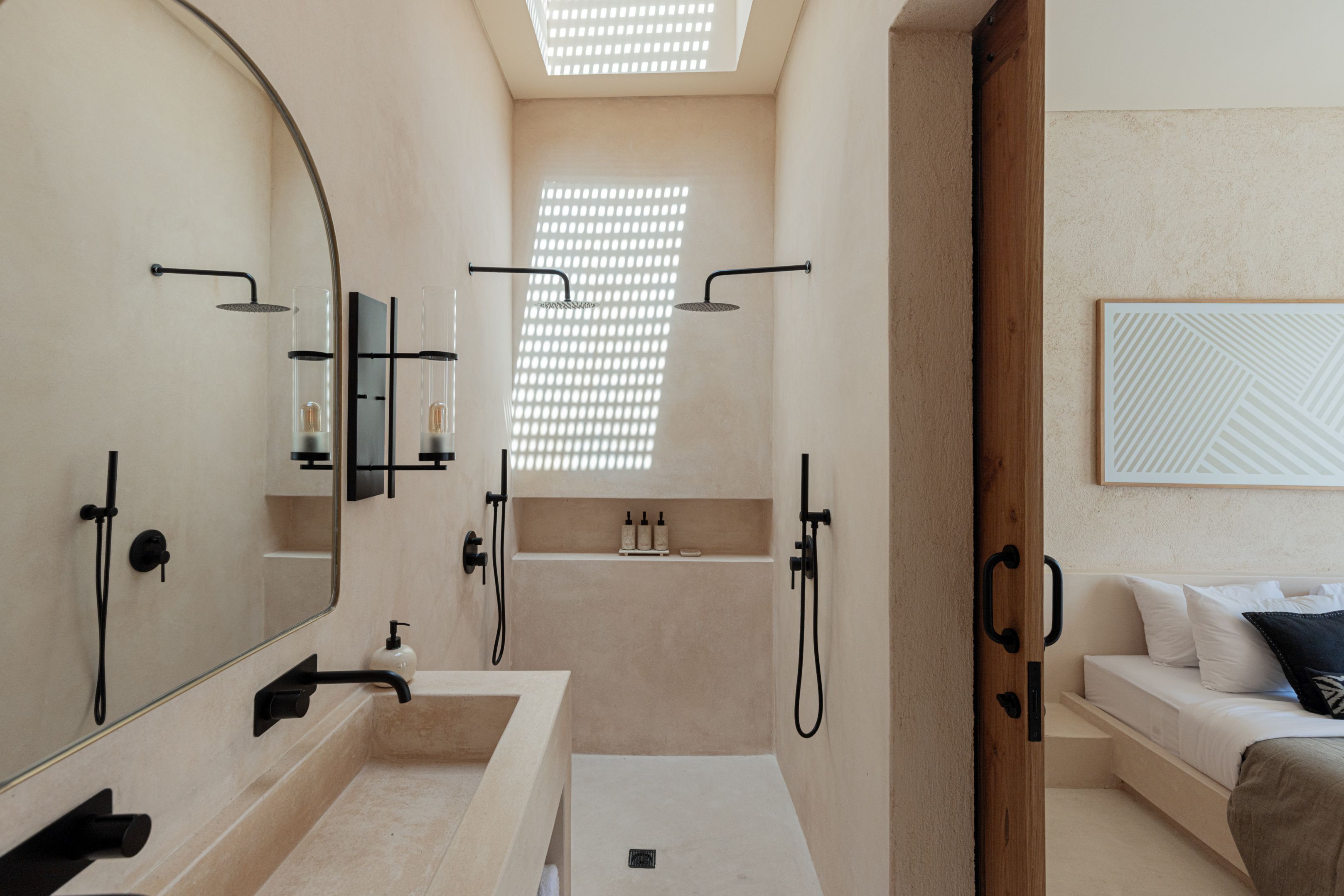 Un baño moderno con un espejo grande, dos lavamanos, ducha e integrado un banco.