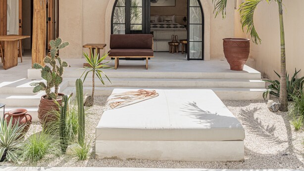 A modern outdoor patio with a pool, a wooden bench, and various plants. - Khaleela Villas (Canggu)