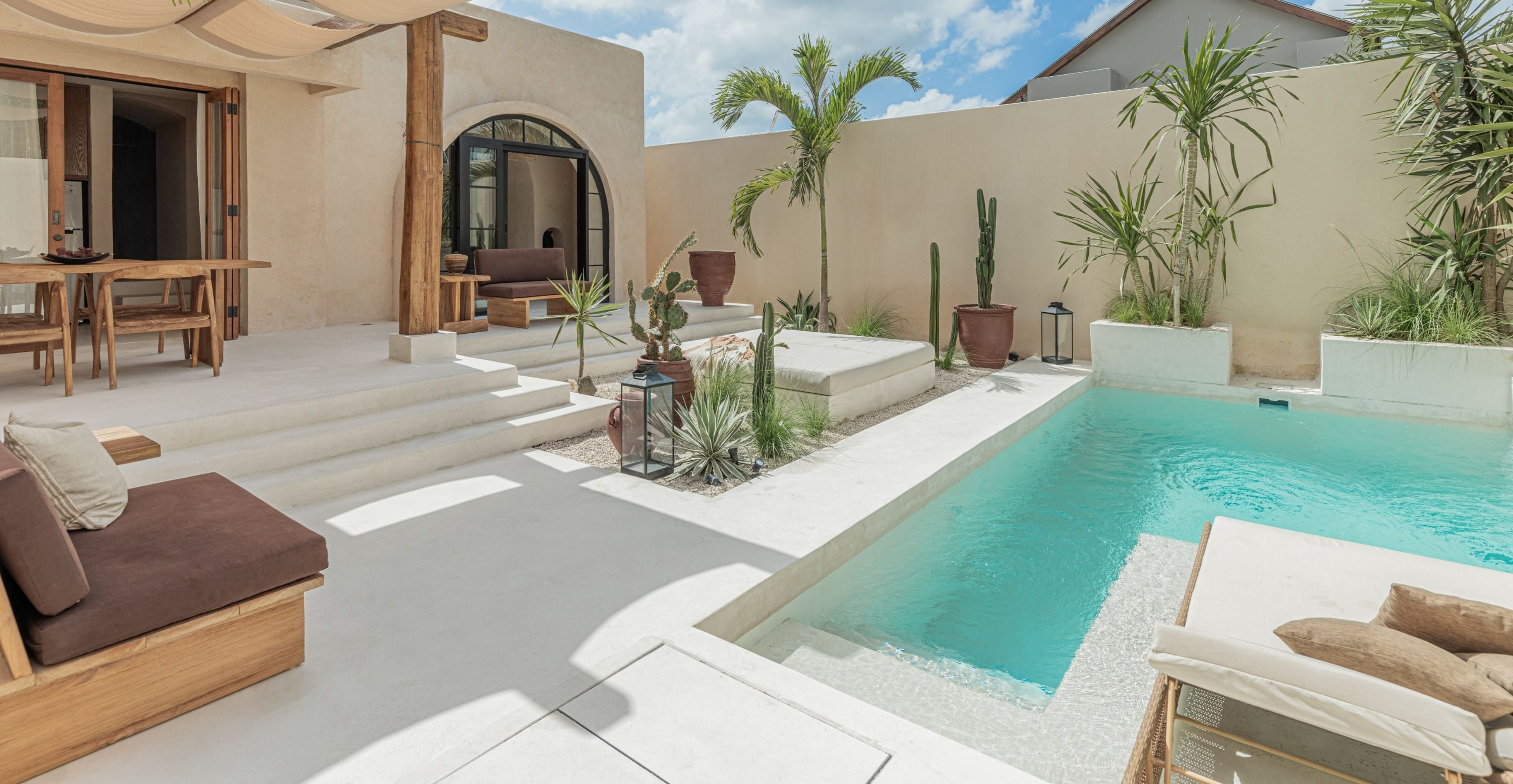 A modern villa with a pool, outdoor seating, and tropical plants.