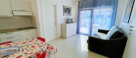 Un espacio habitable compacto con kitchenette, comedor y sofá.