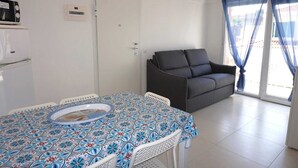 Un espace de vie compact comprenant une table à manger, un canapé et un coin cuisine.