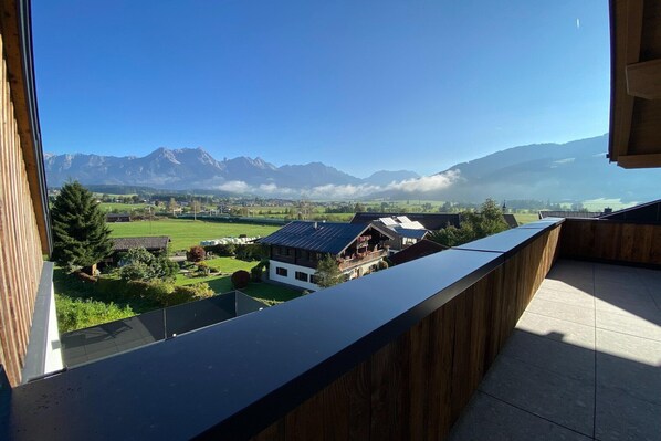 A balcony with a view of a mountain range and a village below.