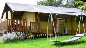 A tented accommodation with a wooden deck, a swing, and a window.