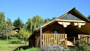 A wooden cabin with a sloped roof, a porch with wooden railings, and a window.