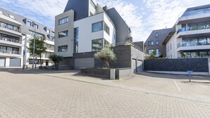 A modern building with a flat roof, large windows, and a paved courtyard.