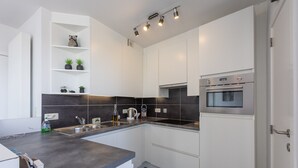 A modern kitchen with white cabinets, a dark backsplash, and a built-in oven.