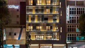 Een modern hotel met meerdere verdiepingen, grote ramen en een goed verlichte gevel.