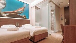 Een moderne hotelkamer met twee bedden, een douche en een bureau.