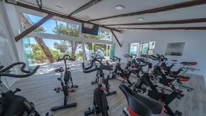 A gym with multiple stationary bikes arranged in rows, large windows offering views of trees and a body of water, and a wooden floor. - Mobile Home Tarragona by Beach & Nature Reserve (Taragona)