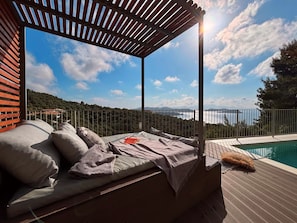A sunlit outdoor seating area with a view of a body of water and hills. - Room-cactus Suberb Suite With Private Po (Skiathos)