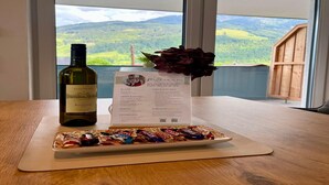 Una botella de vino, un menú y un plato de bombones sobre una mesa con vistas a las montañas.