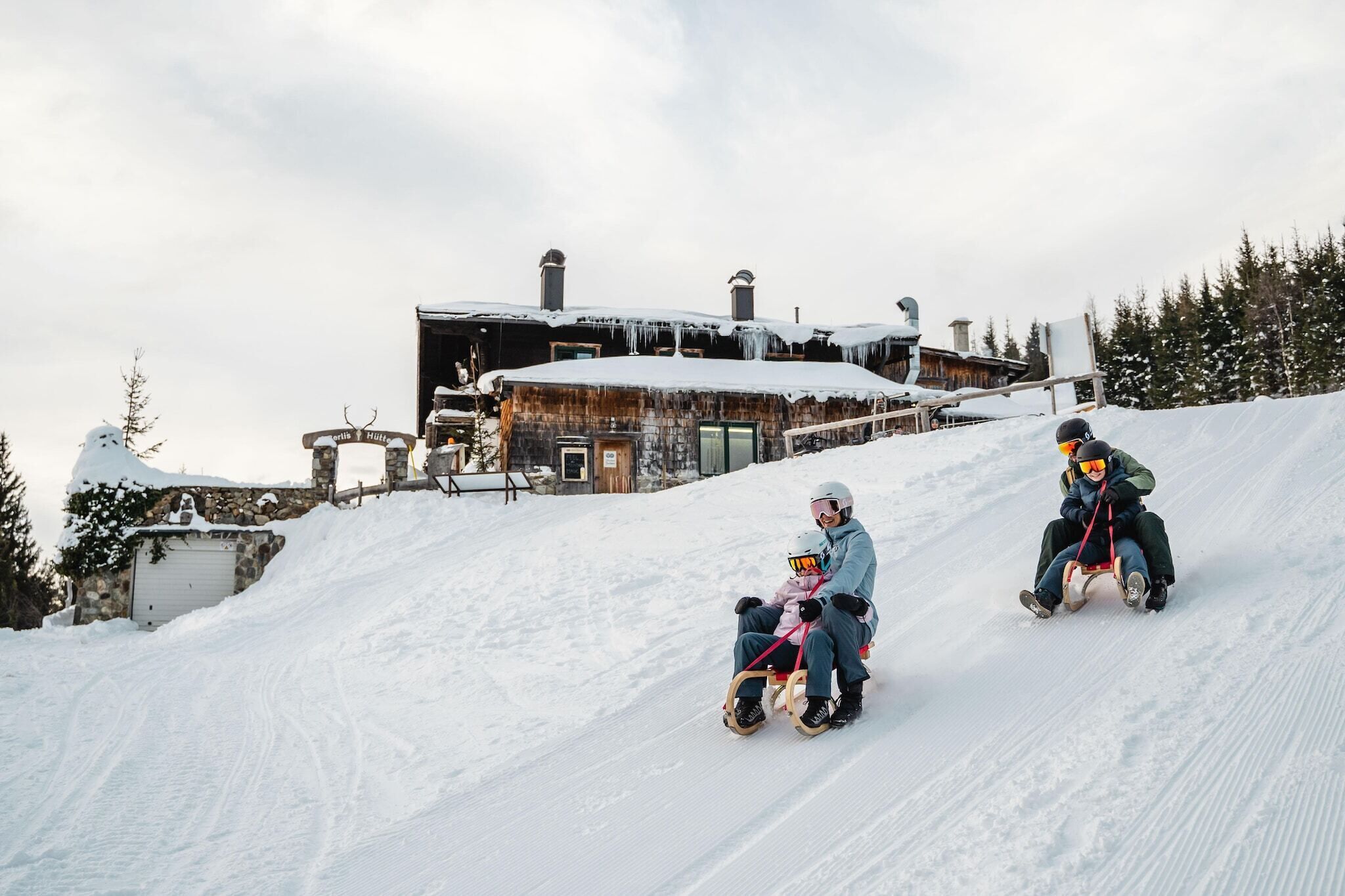A snow-covered slope with a rustic building in the background.