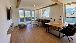 Una sala de estar moderna con una mesa de comedor de madera, un sofá y un televisor montado en la pared.