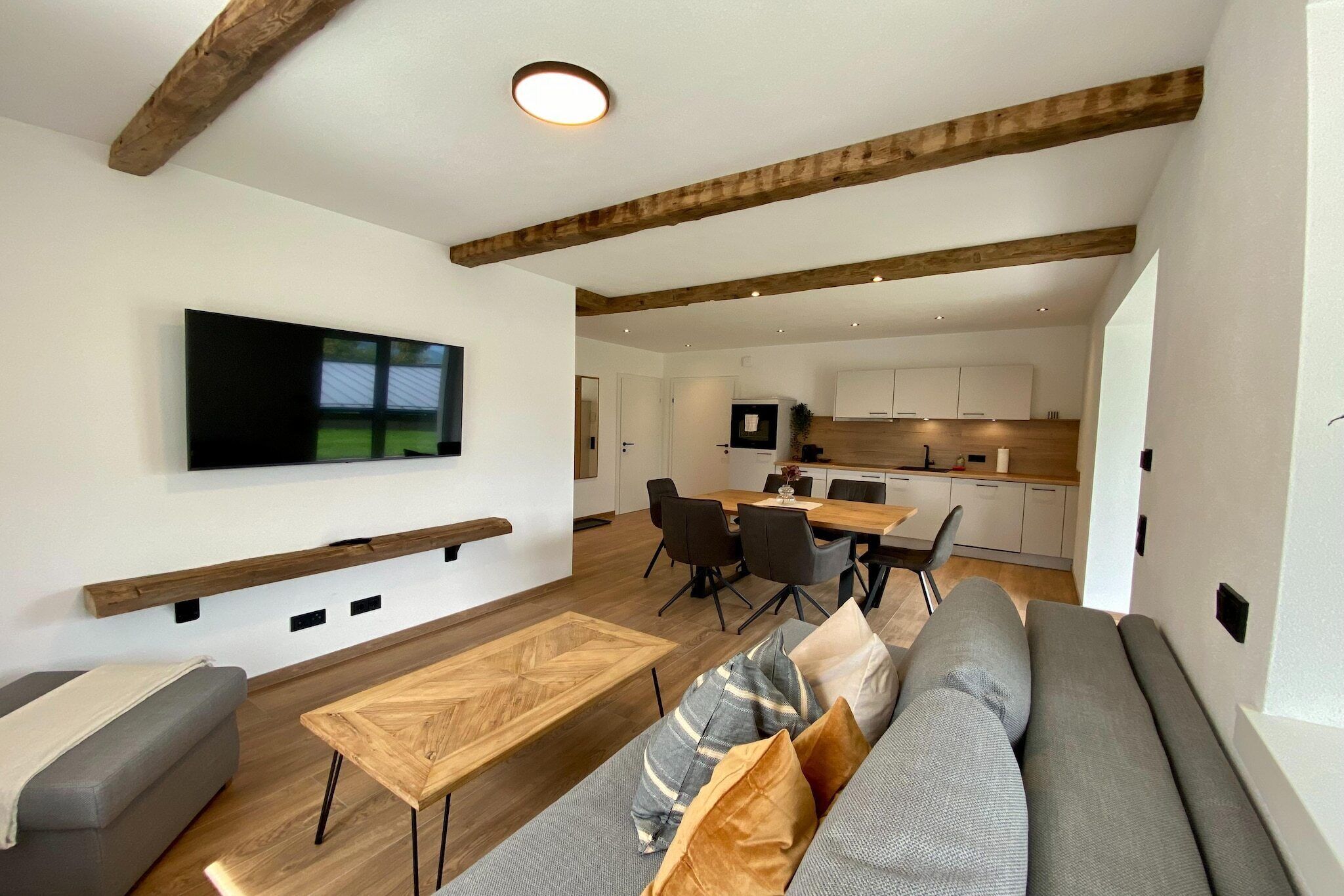 Un salon moderne avec un canapé, une table basse et un téléviseur fixé au mur.