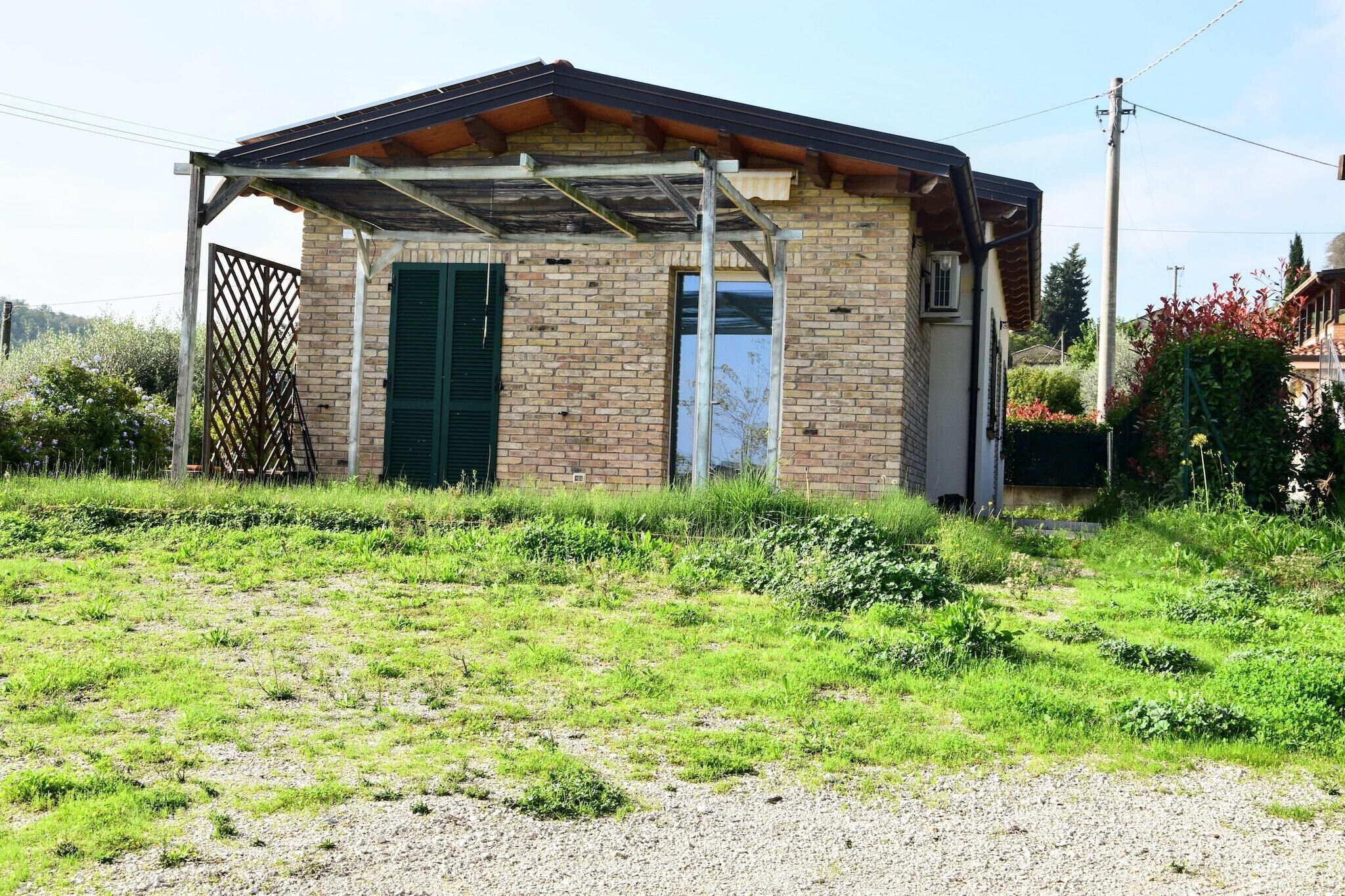 A small brick building with a covered porch and a door with green shutters.