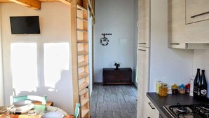 A kitchen with a wooden ceiling, a TV mounted on the wall, and a gas stove. - Apartment in Marche with Pool near Adriatic (Lampedona)
