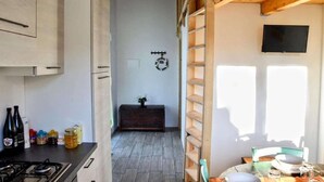 A kitchen with a stove, cabinets, and a dining area with a table set for two. - Apartment in Marche with Pool near Adriatic (Lampedona)