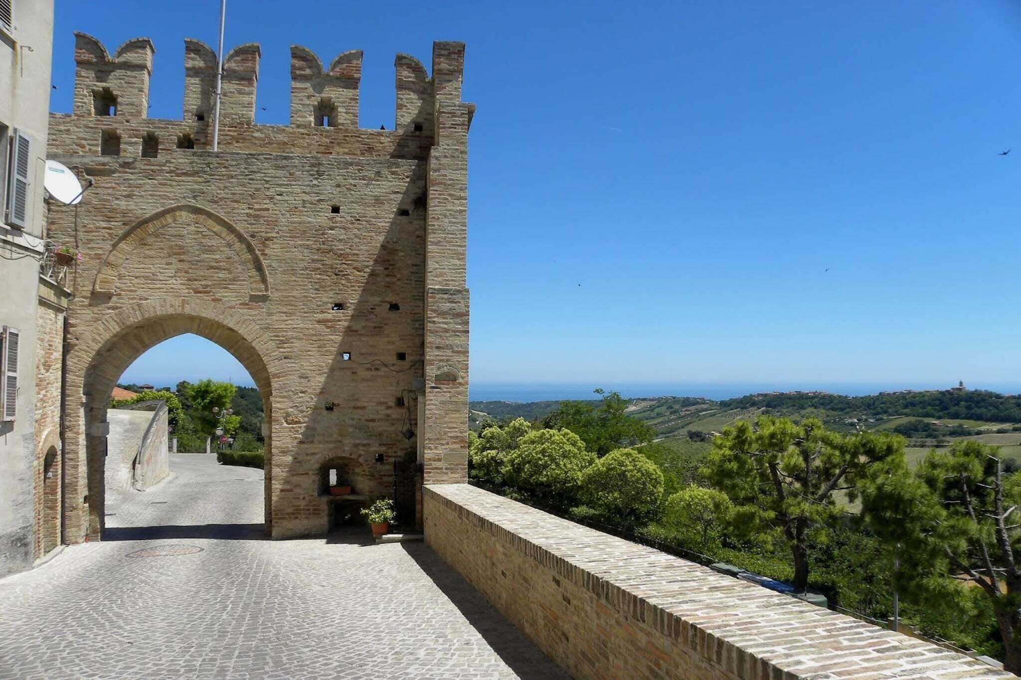 Un arco de piedra que da paso a un patio con vistas al campo.