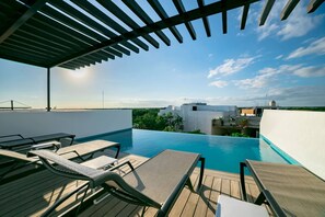 An infinity pool with lounge chairs and a pergola, overlooking a cityscape. - Comfortable, Spacious Penthouse- 2 Bedrooms- 7 People (Tulum)
