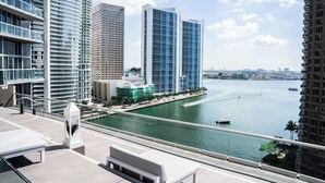 A waterfront view with modern high-rise buildings, a bridge, and a marina.