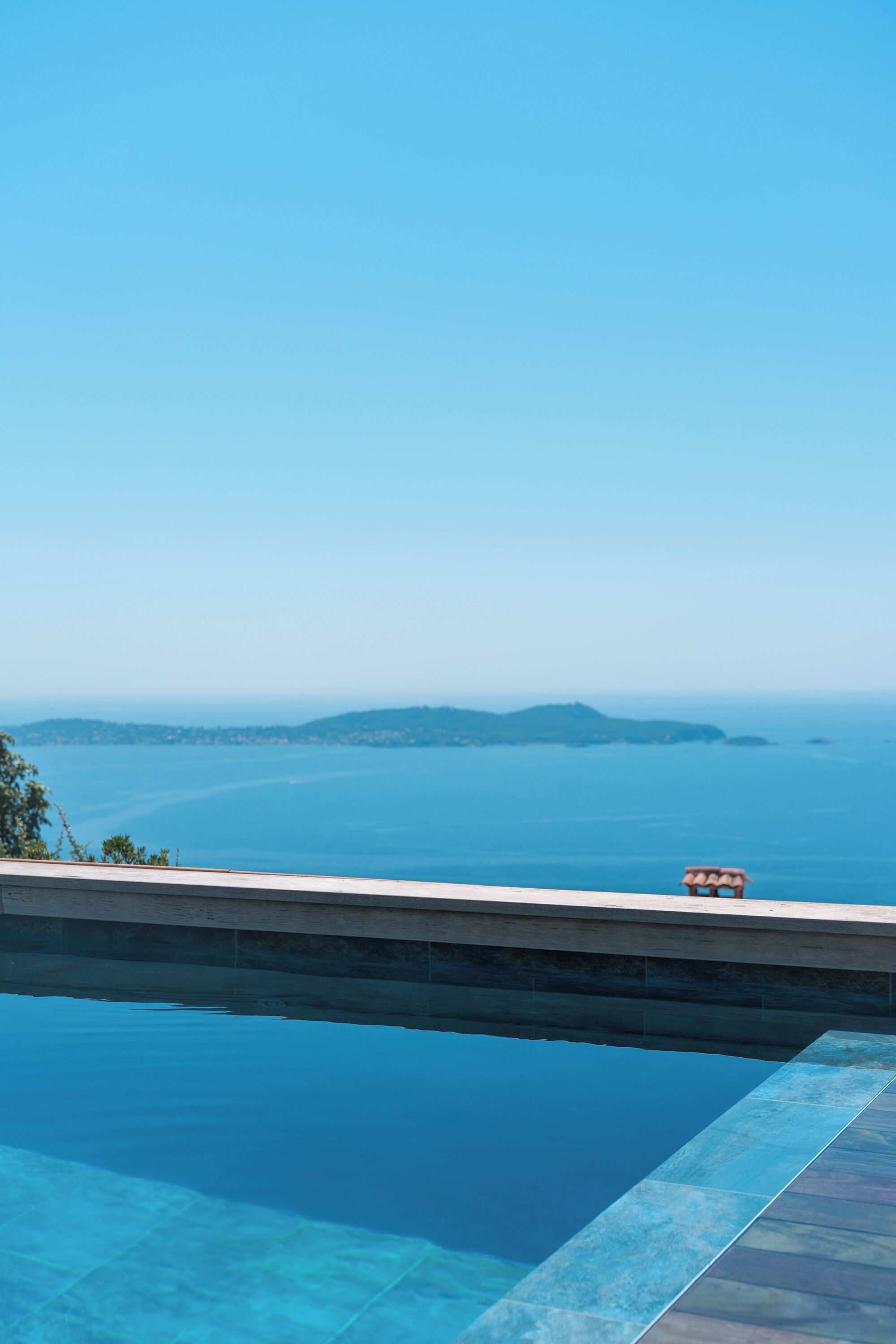 An infinity pool with a clear view of the ocean and distant islands.