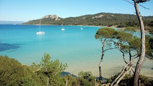 Un paisaje costero con aguas turquesas cristalinas, algunos veleros y montañas al fondo.