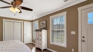Un dormitorio con cama, ventilador de techo, armario y ventana con persianas.