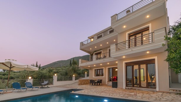 Ein modernes, zweistöckiges Haus mit Swimmingpool, Sitzgelegenheiten im Freien und Blick auf die Hügel.