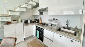 Una cucina moderna con mobili bianchi, piano cottura a gas, forno a microonde e macchina per il caffè.
