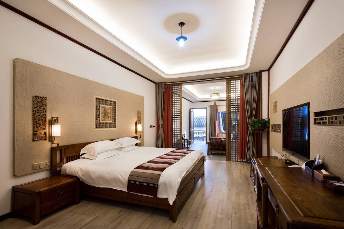 Ein Hotelzimmer mit einem großen Bett, Nachttischen, einem Fernseher und einem Holzbüro.