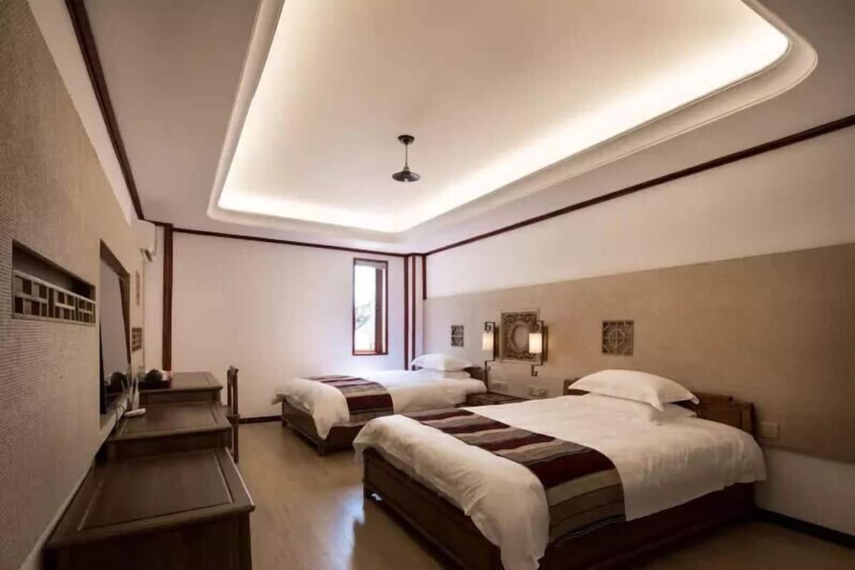 Ein Hotelzimmer mit zwei Betten, einem Schreibtisch und einer Deckenleuchte.
