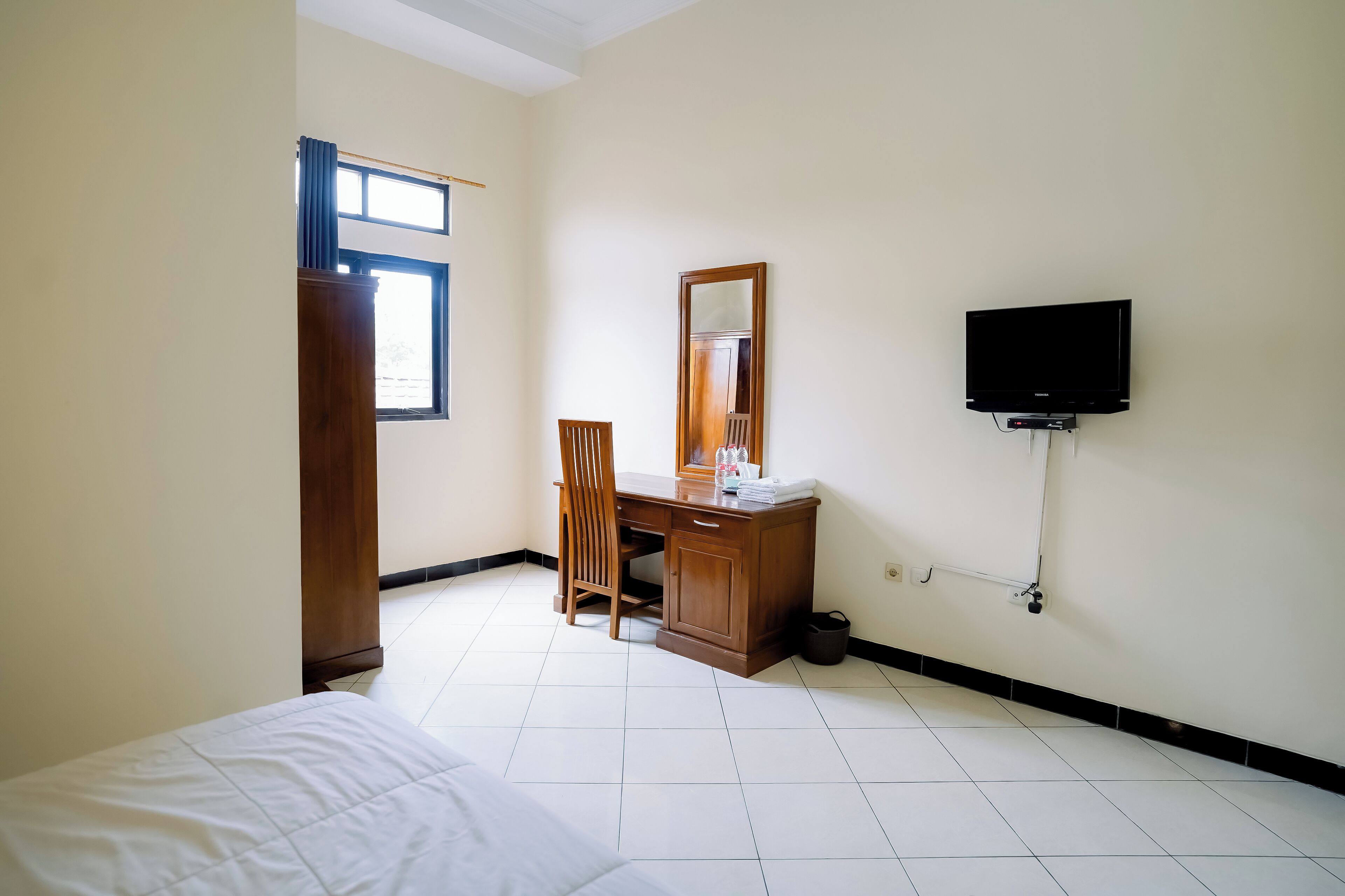 Una habitación de hotel con cama, escritorio, silla, televisor y ventana.