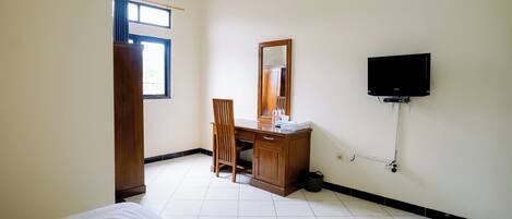 Una habitación de hotel con cama, escritorio, silla, televisor y ventana.