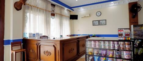 A reception area with a wooden counter, a mounted deer head, a clock, and a snack display.