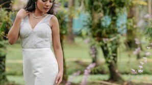 A person in a white gown with a long train, standing on a concrete path in a garden with greenery and flowers. - Village Canopy | wedding venues kochi (Kochi)