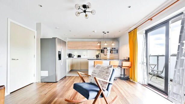 A modern apartment with a kitchen, dining area, and a balcony with yellow curtains.