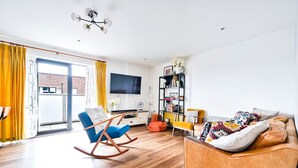 A modern living room with a blue rocking chair, a brown sofa, and a bookshelf.